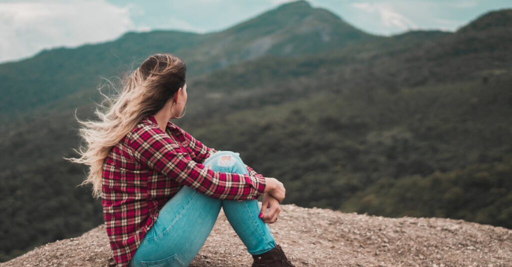 A woman in casual wear enjoys solitude on a scenic Brazilian mountain, embracing a moment of reflection.