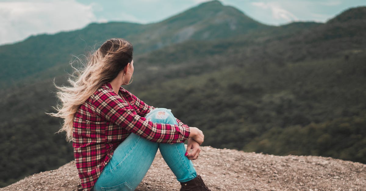 A woman in casual wear enjoys solitude on a scenic Brazilian mountain, embracing a moment of reflection.